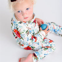 Young girl wearing Floral Christmas Pajamas with bouquets of light blue, white, and red flowers and holly leaves, and personalized with the child's name.