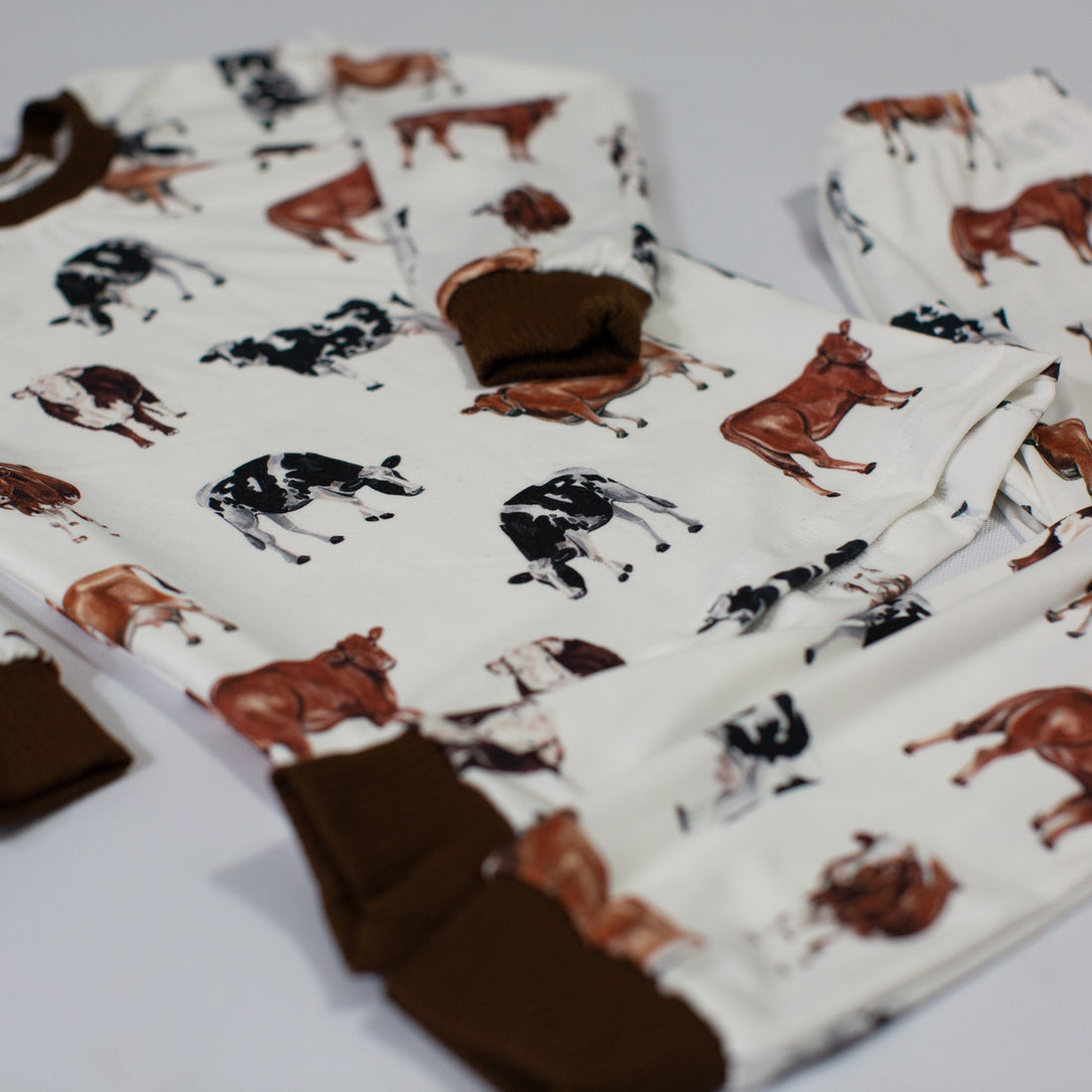 A close up look at the design on our kids cow pajamas. The design has brown and black cows with the brown cuffs on the shirt and pants to match the cow design.