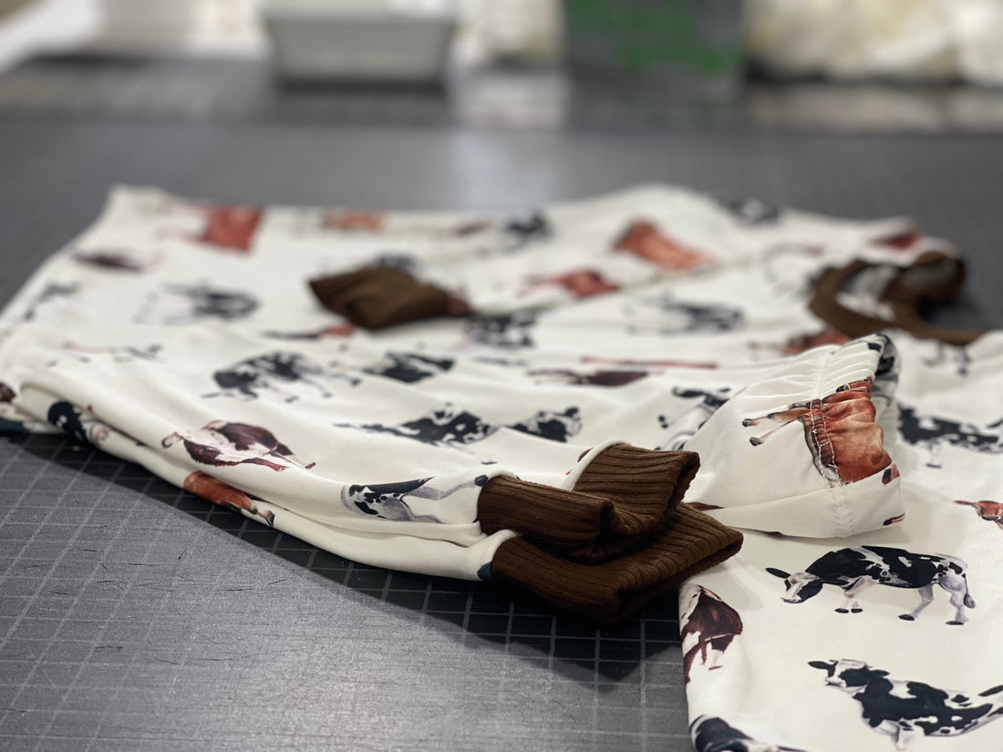 Our personalized cow pajamas nicely folded laying on a black table. The design on the pajamas has three different cows along with brown cuffs on the shirts and pants that matches the design.