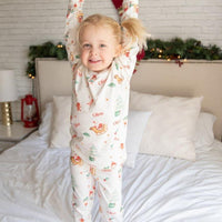 Young girl jumping on the bed in her new Gingerbread Christmas Pajamas.