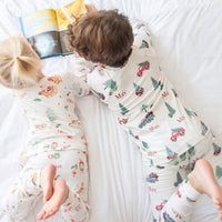 Two kids reading a book together while wearing matching Gingerbread Christmas Pajamas.