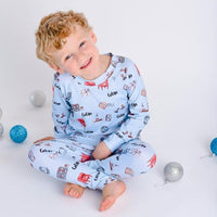 little boy wearing Letters to Santa Christmas pajamas, Holiday images along with letters and mailboxes among our child's name on a light blue background.