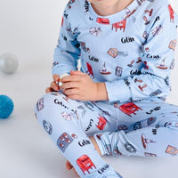 little boy wearing Letters to Santa Christmas pajamas, Holiday images along with letters and mailboxes among our child's name on a light blue background.