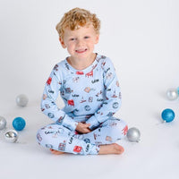 little boy wearing Letters to Santa Christmas pajamas, Holiday images along with letters and mailboxes among our child's name on a light blue background.