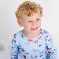 little boy wearing Letters to Santa Christmas pajamas, Holiday images along with letters and mailboxes among our child's name on a light blue background.
