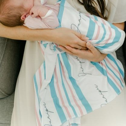 Mom holding her newborn swaddled in our hospital swaddle blanket.