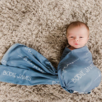 Little baby laying in a personalized camden smokey blue swaddle blanket.