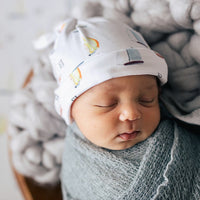 Baby sleeping in their stretchy boat swaddle with a matching sailboat hat.