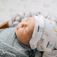 Newborn sleeping in their sailboat swaddle blanket and wearing their matching personalized sailboat hat.