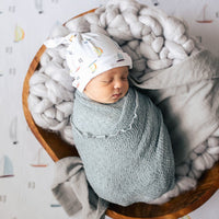Baby sleeping in a bassinet and wrapped up in their personalized boat swaddle.