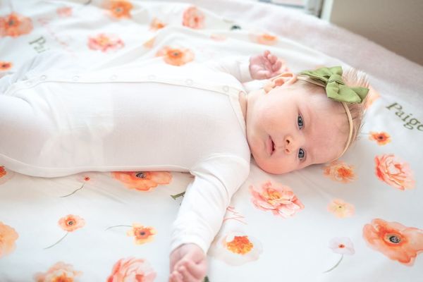 Peach Watercolor Floral Custom Baby Sheet With Baby lying on it A Great Baby