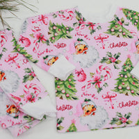 custom holiday sleepwear for little girls, with vintage santa faces and christmas trees with pink bows on a light pink material, name in red script font, and white cuffs.