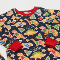 personalized Dino Cookie print Christmas pajamas, navy blue background with dinosaur shaped cookies wearing Christmas sweaters