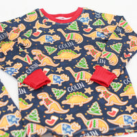 Little boy wearing personalized Dino Cookie print Christmas pajamas, navy blue background with dinosaur shaped cookies wearing Christmas sweaters