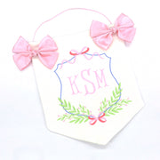 white and pink door hanging banner with baby's embroidered initials, two pink bows and a string for hanging on nursery or hospital door.