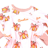 personalized Halloween nightwear for kids, pink pajamas with pumpkins and bows and little girls name, with pink cuffs.