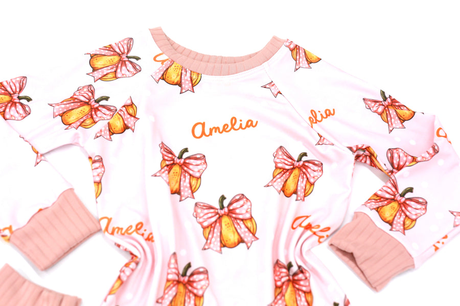 personalized Halloween nightwear for kids, pink pajamas with pumpkins and bows and little girls name, with pink cuffs.