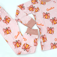 personalized Halloween nightwear for kids, pink pajamas with pumpkins and bows and little girls name, with pink cuffs.