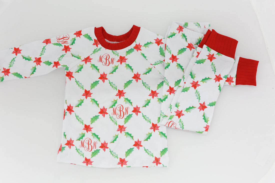 personalized Holiday Pajamas for Girls with coquette style lattice holly leaf print, red ribbins, and initials monogrammed in red, on white jersey knit background and red cuffs.