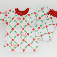 personalized Holiday Pajamas for Girls with coquette style lattice holly leaf print, red ribbins, and initials monogrammed in red, on white jersey knit background and red cuffs.