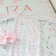 Baby outfit with floral design and matching headband on a pink floral background