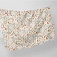 a white fabric with a floral pattern, including various flowers, leaves, and butterflies. The fabric appears to be hanging on a line, creating a visually appealing and decorative piece.