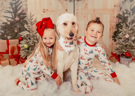 little kids wearing Christmas in the Forest soft and stretchy Christmas Pajamas with forest animals, trees, and pinecone bundles decorated for the holidays, on white fabric and red cuffs, with child's name scattered among the images.