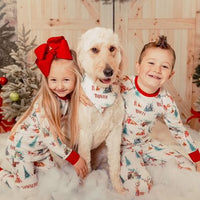 little kids wearing Christmas in the Forest soft and stretchy Christmas Pajamas with forest animals, trees, and pinecone bundles decorated for the holidays, on white fabric and red cuffs, with child's name scattered among the images.