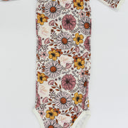A long-sleeved onesie with a floral print pattern, featuring various colors and shapes of flowers and leaves.