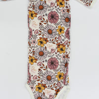 A long-sleeved onesie with a floral print pattern, featuring various colors and shapes of flowers and leaves.