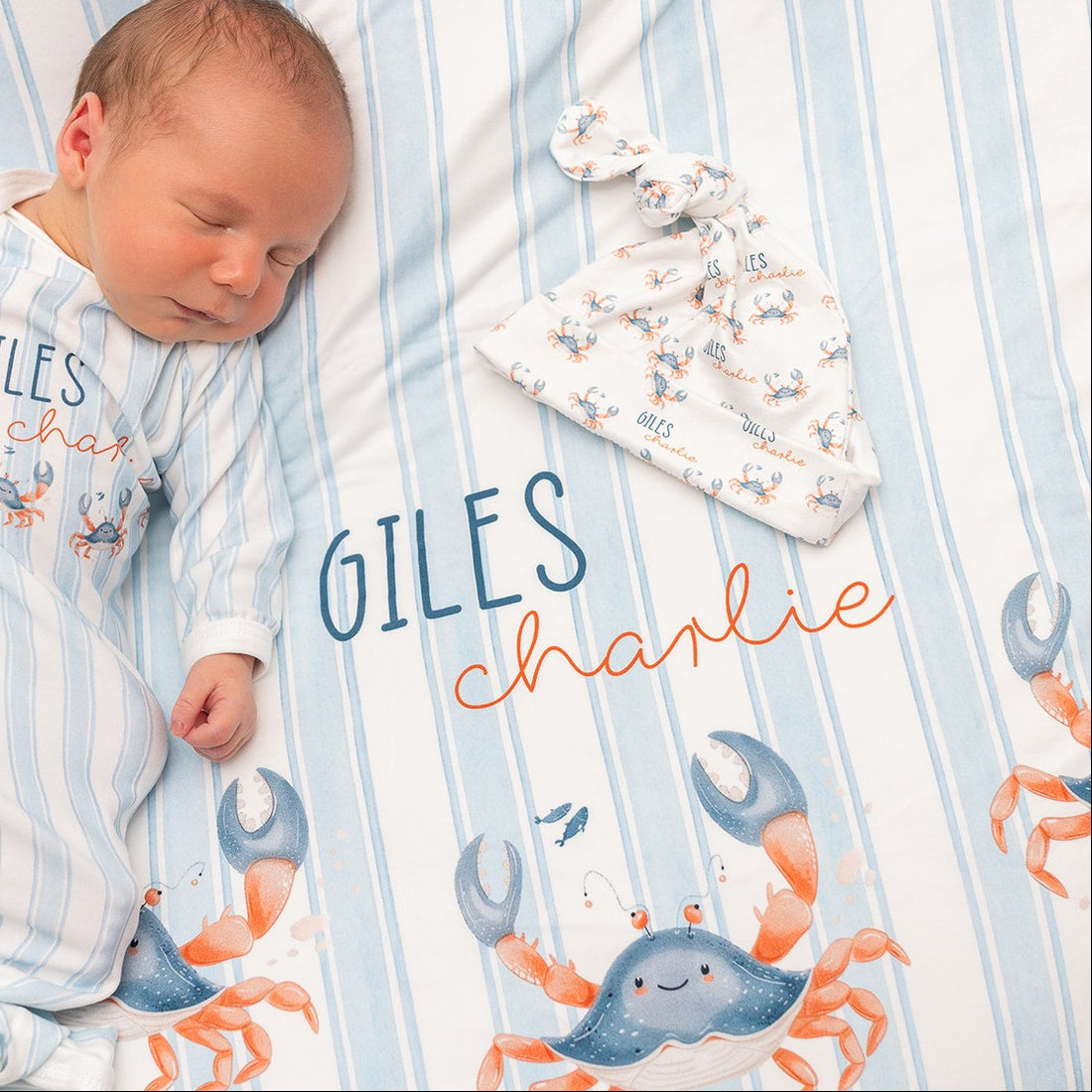 Newborn baby wrapped in a swaddle with crab pattern on a soft white blanket
