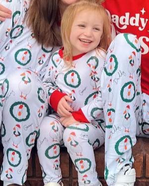 little girl wearing festive christmas silly goose personalized pajamas, white background with white geese in santa hats surrounded by a wreaths, personalized with name scattered among the geese.