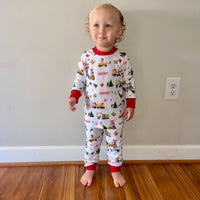 little boy wearing Christmas Construction custom holiday pajamas with construction vehicles in santa hats and christmas trees, featuring child's name in red letters and red cuffs.