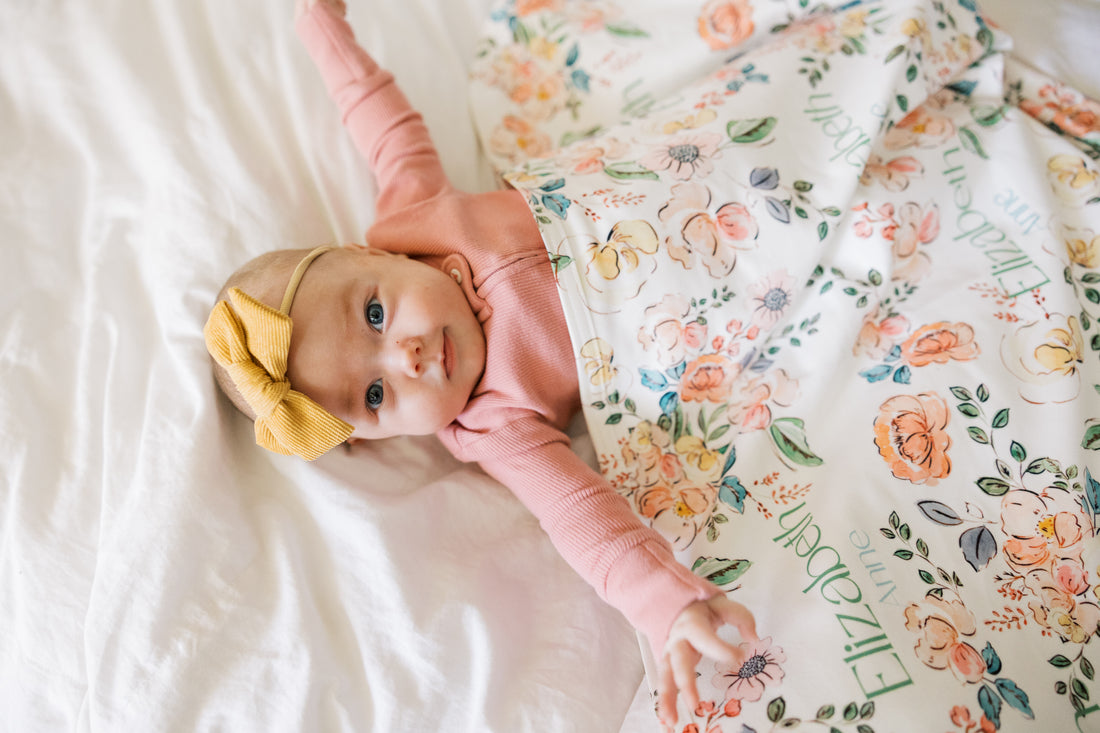 Baby wrapped in personalized keepsake blanket with satin trim