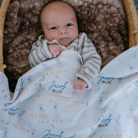 soft white baby blanket with geese and personalized name draped across baby boy in bassinet