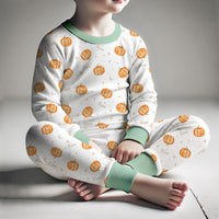 personalized fall pajamas for little boys that have orange cartoon pumpkins and child's name in light brown letters on ivory fabric with green cuffs.