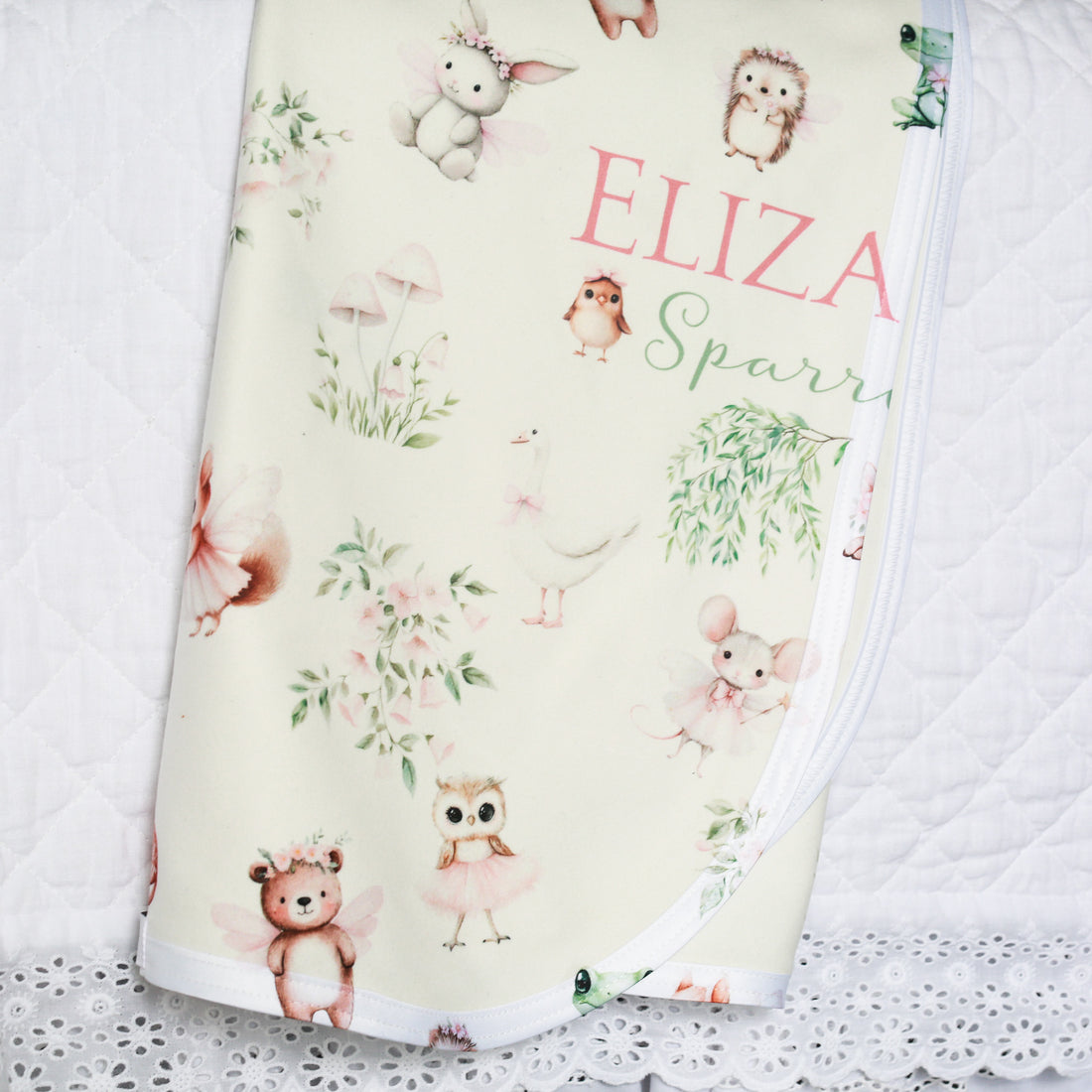 Baby blanket with animal patterns and the name 'Eliza Sparrow' on a white lace background