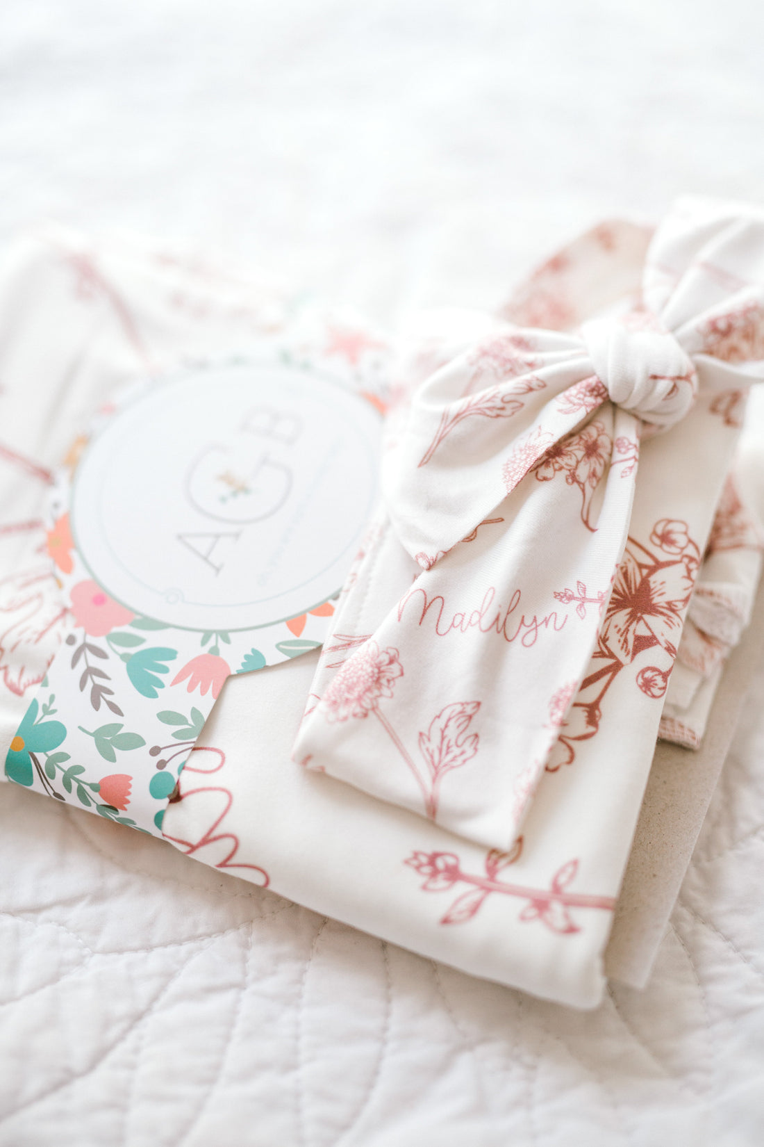 A white cloth with a floral pattern and a bow tied around it, along with a small circular tag that says "AGB".