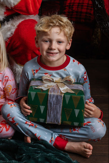 child wearing personalized christmas pajamas with santa on skateboards on blue background with red cuffs