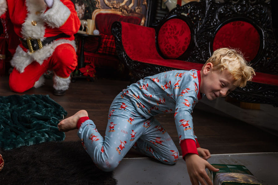 child wearing personalized christmas pajamas with santa on skateboards on blue background with red cuffs