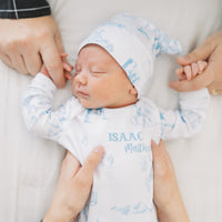 baby boy in tie bottom baby gown with light blue western toile print personalized with name and matching knotted hat