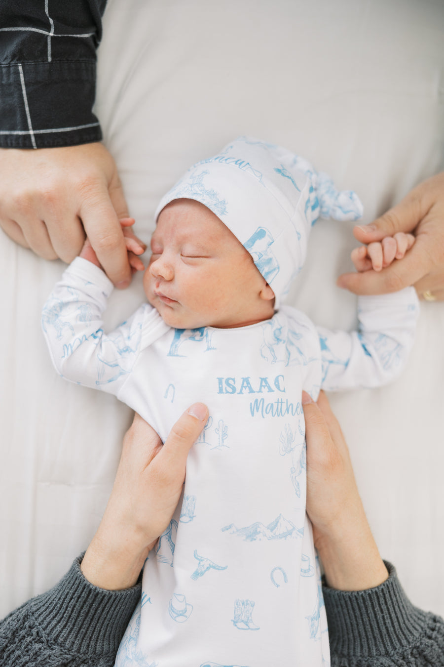 baby boy in tie bottom baby gown with light blue western toile print personalized with name and matching knotted hat