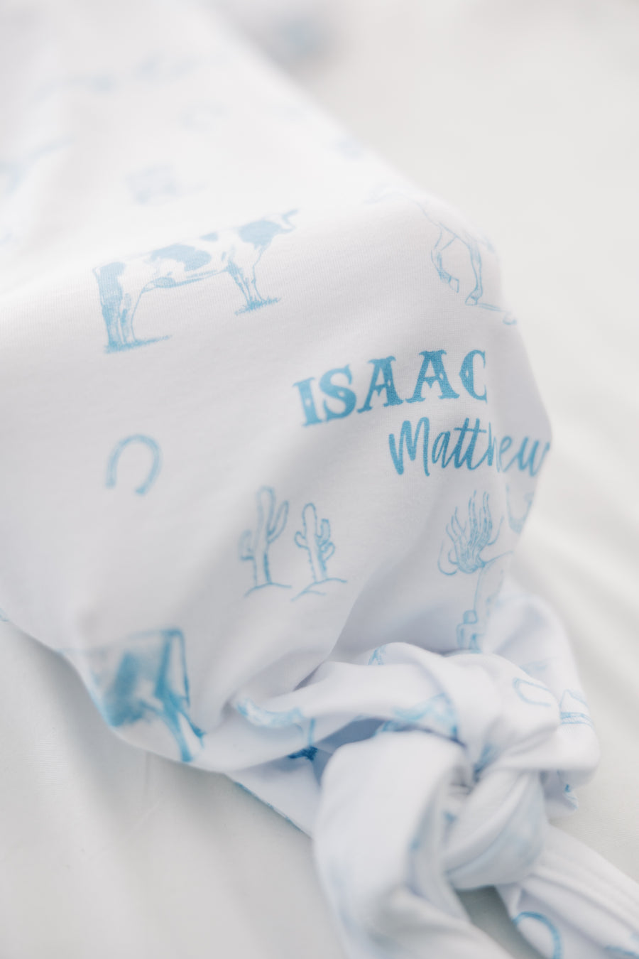 baby boy in tie bottom baby gown with light blue western toile print personalized with name and matching knotted hat