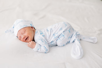 baby boy in tie bottom baby gown with light blue western toile print personalized with name and matching knotted hat