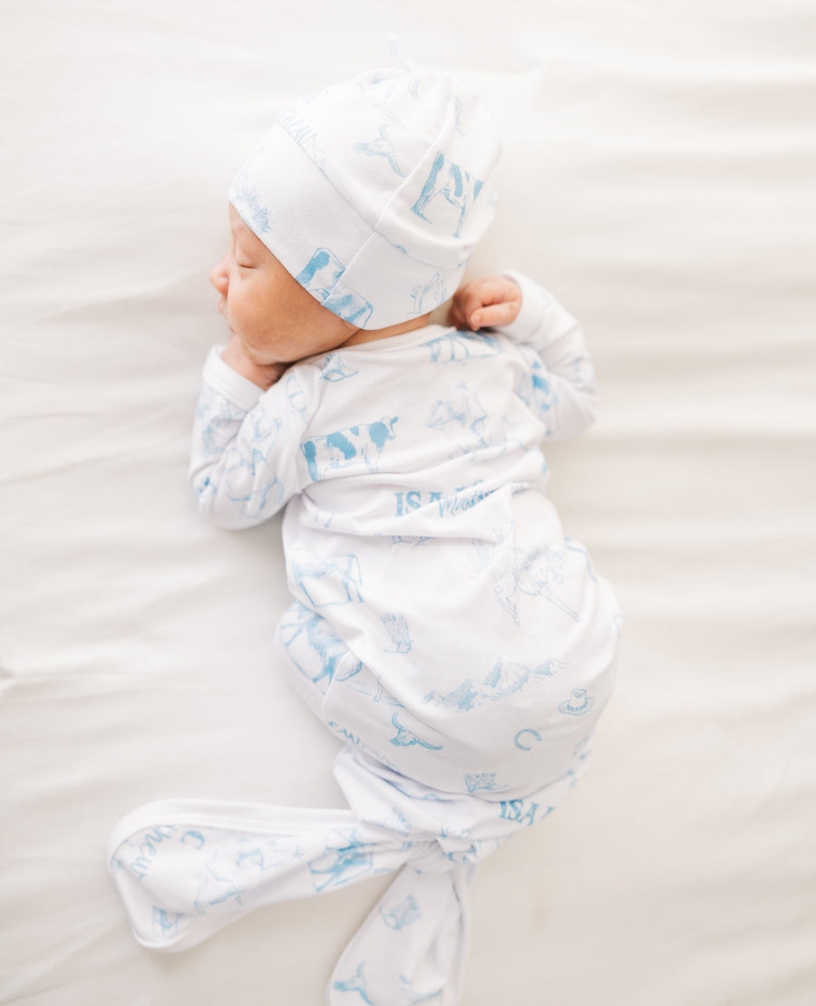 baby boy in tie bottom baby gown with light blue western toile print personalized with name and matching knotted hat