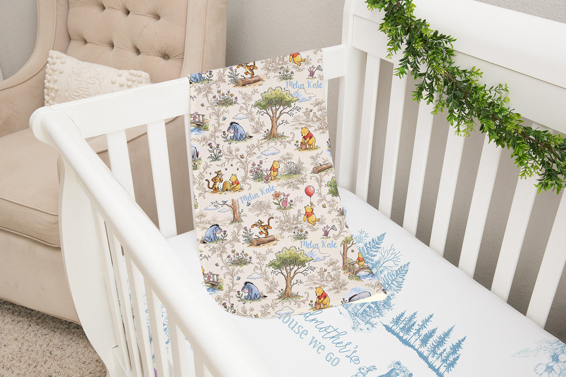 A white crib with a Winnie the Pooh-themed blanket and a beige armchair in the background.