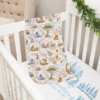 A white crib with a Winnie the Pooh-themed blanket and a beige armchair in the background.