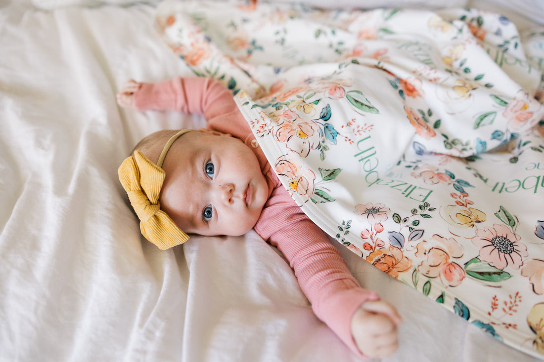 Baby wrapped in personalized keepsake blanket with satin trim
