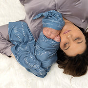 Little baby laying next to mom in a camden smokey blue swaddle blanket. 