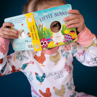 Child reading a book and being playful while she is wearing her personalized chicken pajamas. 